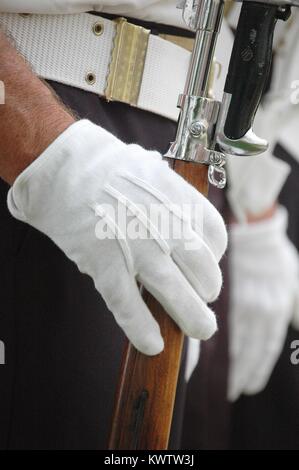 Guanto bianco coperti mano destra afferra un fucile mentre in piedi in uniforme in corrispondenza di attenzione. Stretta di mano e la cinghia. Foto Stock