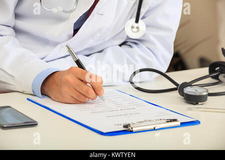 Medico di riempimento di una forma medica sulla sua scrivania Foto Stock