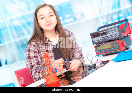 Schoolgirl in robot di laboratorio microcontrollore di debug Foto Stock