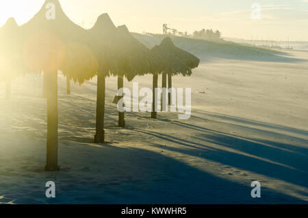 Sovraesposte spiaggia vista serale con molti ombrelloni da sole al tramonto Foto Stock