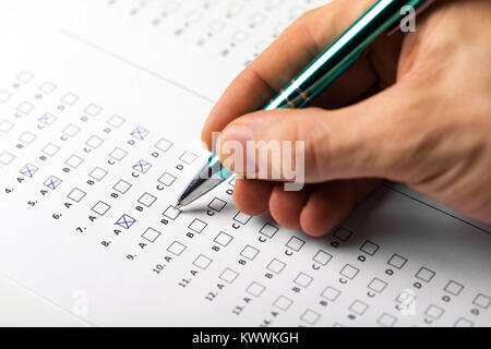 Mano dello studente con il riempimento della penna in un esame di risposta del test del foglio Foto Stock