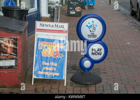 Segni sul marciapiede fuori da un negozio di giornalai pubblicità la lotteria nazionale e quotidiani Foto Stock