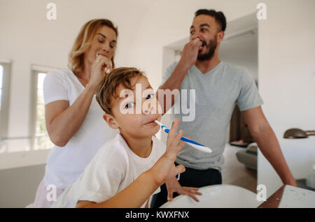 Little Boy spazzolare i denti con i suoi genitori in bagno. Famiglia spazzolare i denti insieme in bagno. Foto Stock