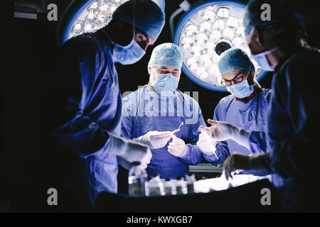 Un gruppo di professionisti medici di eseguire l'intervento chirurgico nel funzionamento del teatro. Team di medici in ospedale in sala operatoria. Foto Stock