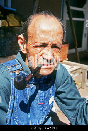 Un anziano uomo ispanico indossando tute, sul suo portico a Lincoln, Nuovo Messico Foto Stock