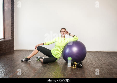 La perdita di peso. Numerose attrezzature per il fitness. Sportivo da donna la relaxina sul pavimento. Studio shot Foto Stock