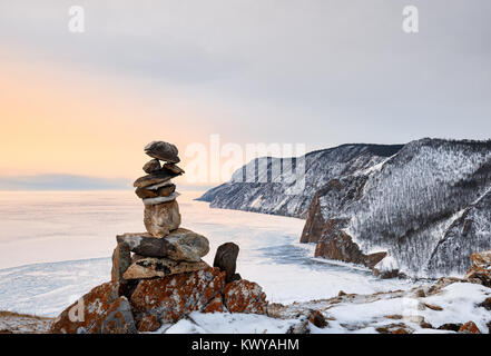 La piramide di pietre sopra il lago di ghiaccio. Alba sul lago Baikal in marzo. Olkhon Island. Regione di Irkutsk. La Russia Foto Stock