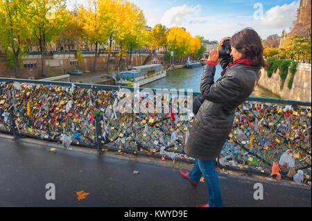 Parigi turistica Senna, vista in autunno di una femmina di turismo scattando una foto di serrature d'amore attaccato al Pont de l'Archeveche a Parigi, Francia. Foto Stock