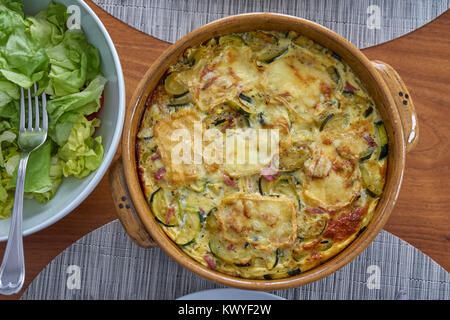 Flan di zucchine servita su un tavolo di legno vestito con Insalatiera e Soufflenheim in ceramica Foto Stock