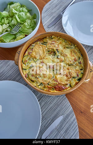 Flan di zucchine servita su un tavolo di legno vestito con Insalatiera e Soufflenheim in ceramica Foto Stock