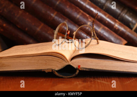 Vintage vita ancora con molto vecchi occhiali giacente sul libro aperto vicino a scaffale Foto Stock