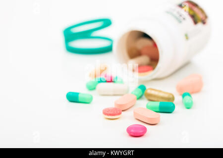 Pillole al di fuori di un bottiglia su sfondo bianco Foto Stock
