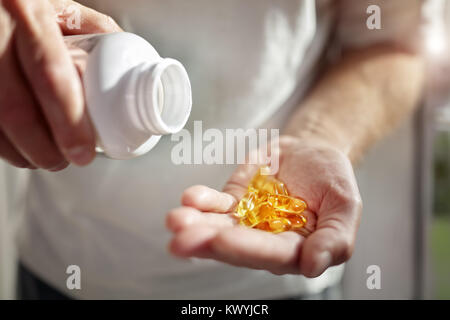 Bottiglia di omega 3 olio di pesce capsule versando in mano Foto Stock