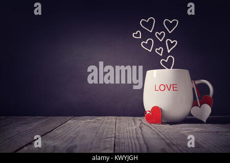 Amore scritto su una tazza con il concetto di cuori per il giorno di San Valentino o la festa della mamma sfondo con spazio di copia Foto Stock