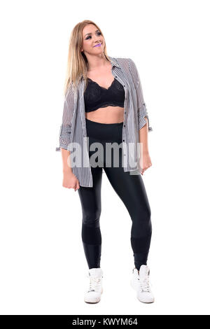 Giovani attraenti danza jazz donna in piedi nella camicia a righe mentre guardando verso l'alto e sorriso. Corpo pieno lunghezza ritratto isolato su sfondo bianco. Foto Stock