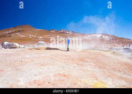 Tourist guardando fumante stagni di acqua e fango pentole nella regione geotermica di Huayllajc su altipiani andini della Bolivia. Foto Stock