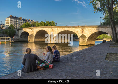 Francia, Parigi (75), Donna fare picnic sul Quai de Bourbon con il Pont Marie dietro Foto Stock