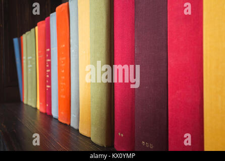 Libri antichi in custodie colorate stand sul ripiano di legno Foto Stock