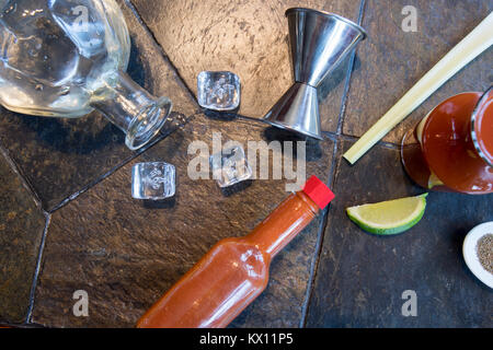 Bloody Mary o Cesare cocktail Ingredienti decostruito sul piano portapaziente in ardesia con cubetti di ghiaccio e colpo di vetro con copia spazio, Foto Stock