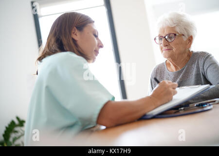 L'infermiera dando la prescrizione di donna anziana Foto Stock