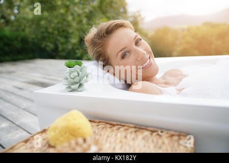 Bella donna di relax nella vasca da bagno esterna Foto Stock