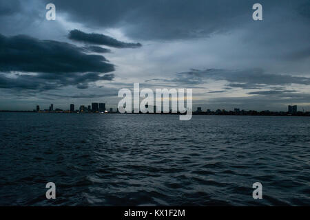 Phnom Penh tramonto tramonto visto dal Mekong e il Tonle Sap fiumi, emergono con sky raschiatori. Stagione dei monsoni e la pioggia nuvole avvicinando alla città Foto Stock