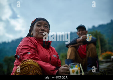 Gurung donna e uomo bere il tè, Chomrong, Annapurna massif, Nepal Foto Stock