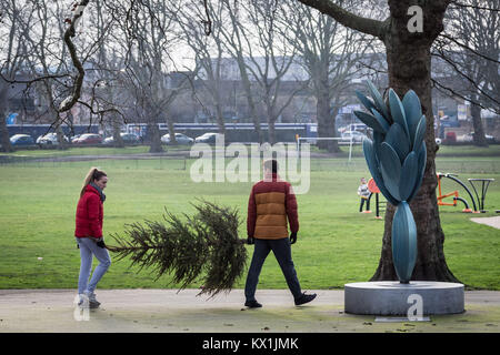 Londra, Regno Unito. Il 6 gennaio, 2018. Una giovane coppia prendono il loro albero di Natale al Consiglio un punto di riciclaggio nel Parco Deptford Credito: Guy Corbishley/Alamy Live News Foto Stock