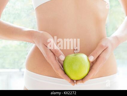 Modello rilasciato. Giovane donna azienda mela verde, vicino. Foto Stock