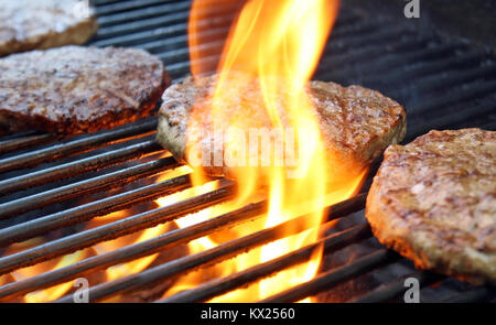 Gli hamburger la cottura sul fuoco sulla griglia Foto Stock