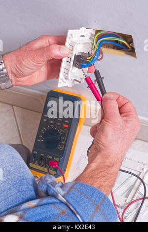 Per elettricista mani assembla un bipolare standard di presa di corrente a muro. Foto Stock