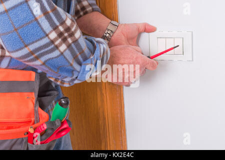 Per elettricista mani assembla un bipolare standard di presa di corrente a muro. Foto Stock