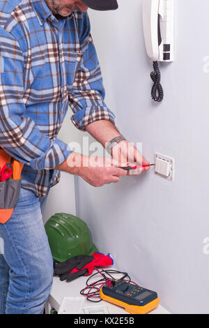 Per elettricista mani assembla un bipolare standard di presa di corrente a muro. Foto Stock