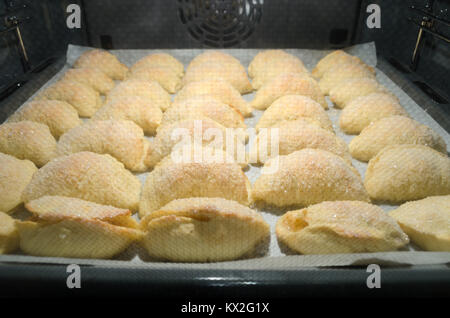 Set di dolci fatti in casa il lievito brioche coperta di cristalli di zucchero e riempito con le mele durante la cottura all'interno di home forno del pane. Foto Stock