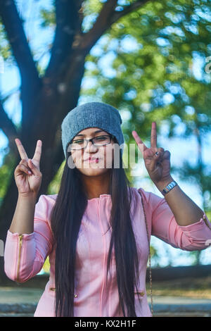 Ragazza sorridente che mostra il simbolo di pace Foto Stock