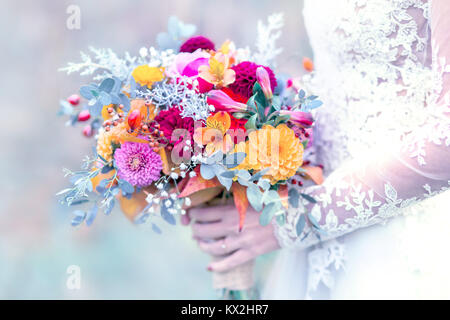 Colorate bouquet di nozze in sposa mano con lacy bianco abito da sposa dettaglio Foto Stock