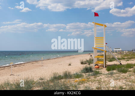 Torre di salvataggio con una bandiera rossa sulla spiaggia del resort village Commissario Vitórino nel quartiere Saksky della Crimea, Russia Foto Stock