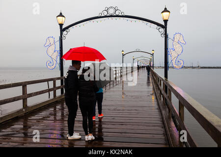 La gente che camminava sul bagnato, ventoso, molo di roccia bianca, British Columbia Foto Stock