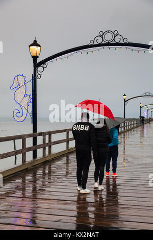 La gente che camminava sul bagnato, ventoso, molo di roccia bianca, British Columbia Foto Stock