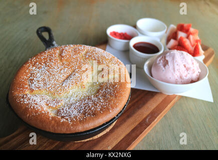 Souffle soffici Pancake con fragole fresche a pezzi e gelato sul vassoio in legno Foto Stock