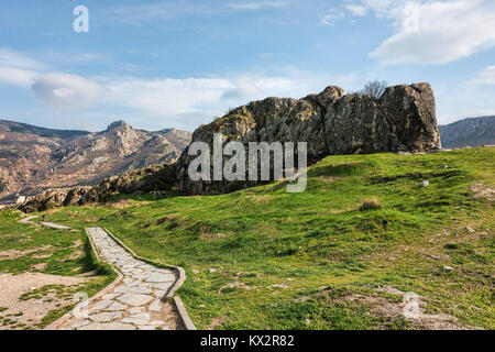 Passeggiata nel verde paesaggio sotto il cielo blu con soffici nuvole formazioni rocciose e le montagne in distanza Foto Stock
