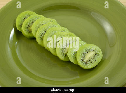 Close up di fettine di kiwi verde sulla piastra come snack o in preparazione per essere utilizzato come ingrediente di cottura Foto Stock