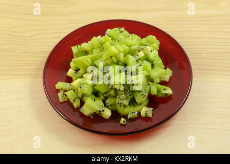 Close up di polpa di kiwi sulla targhetta rossa in preparazione per essere utilizzato come ingrediente di cottura Foto Stock