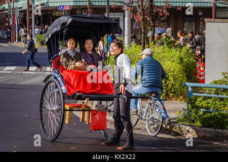 TOKYO, Giappone - 15 novembre 2015: Unidentified rickshaw driver con i passeggeri nella stazione di Asukusa vicino fiume Sumida Foto Stock