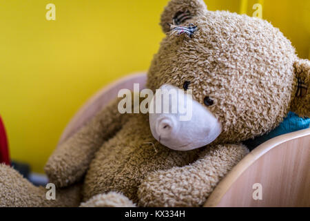 Vecchio orso di teddy lasciato solo in una sedia per bambini Foto Stock