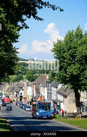 Vista lungo la collina via dello shopping con un bus in primo piano, burford, Cotswolds, Oxfordshire, Inghilterra, Regno Unito, Europa occidentale. Foto Stock