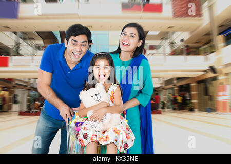 La famiglia felice spingendo il carrello di shopping nel centro commerciale avente fun allegro Foto Stock