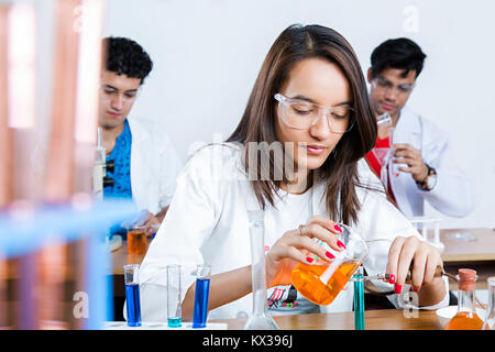 1 Indian studente di college versando il liquido chimico di ricerca scoperta di laboratorio Foto Stock