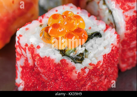 California rotoli con uova di salmone e pesci volanti con anguille e formaggio Filadelfia closeup. Macro. Foto Stock