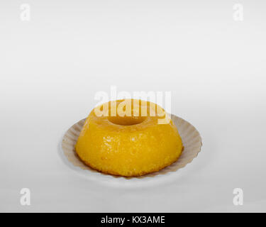 Quindim, un gustoso brasiliano giallo dolce fatto con latte condensato e uova, visto di lato e isolato su sfondo bianco Foto Stock